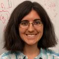 Tamara Broderick smiling at the camera in front of a white board covered with math