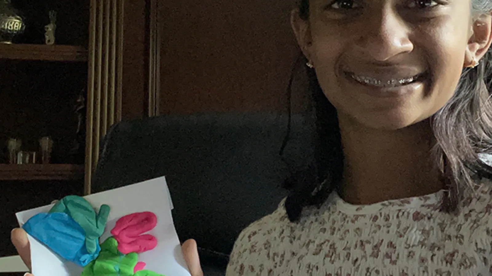 A Zoom image of a summer camp student holding the model of a brain she created