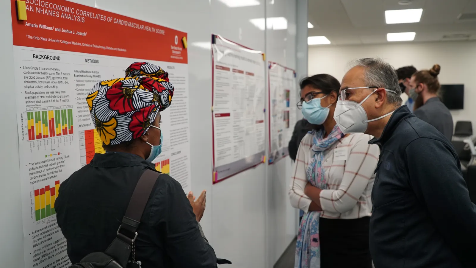 A woman explains her research poster to two men at the Fall Forum poster session 