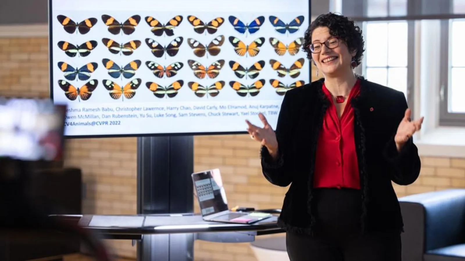 Tanya Berger-Wolf giving a talk in front on a screen showing kinds of butterflies