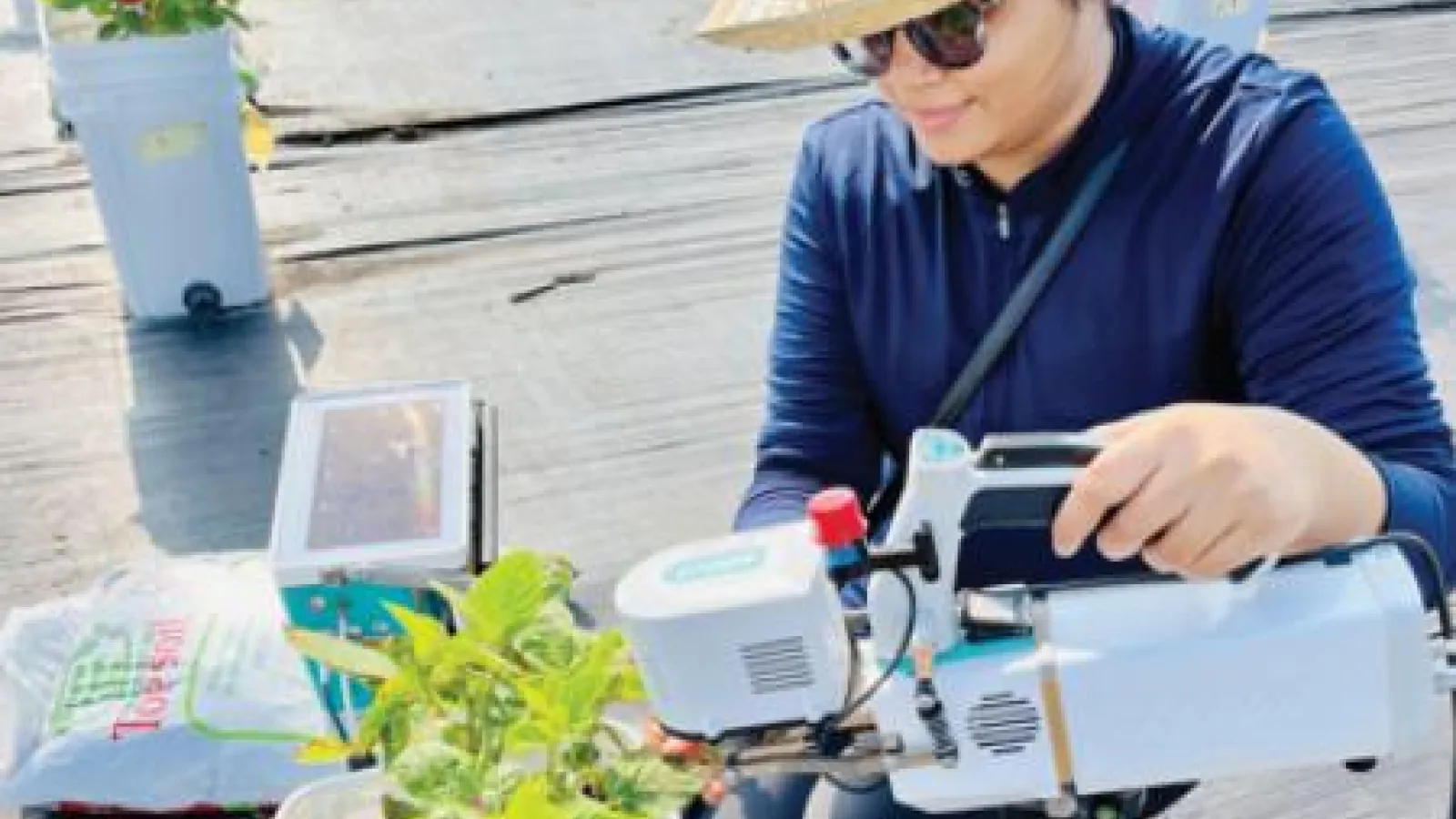 Srishti Gaur pointing a research device at a potted plant