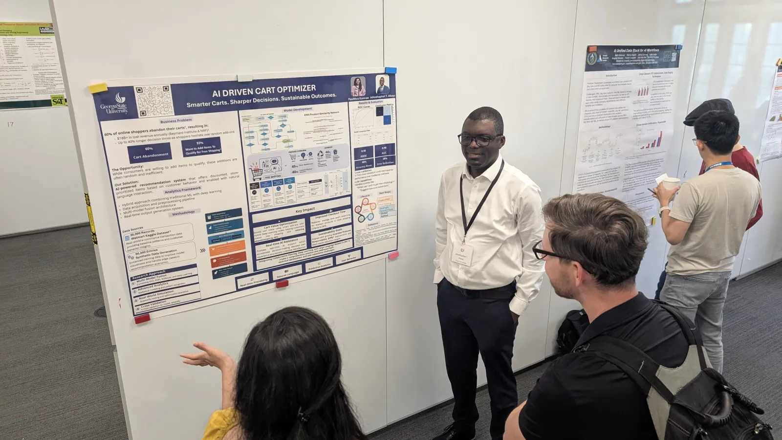 Conference Attendees listening to someone discuss their poster and research