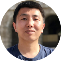 Headshot of Ayonga Hereid smiling, wearing a collared shirt and jacket, with a blurred campus background.