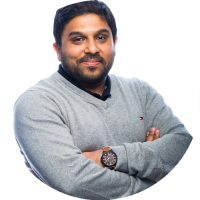 Headshot of Rajeev Chhajer smiling slightly, wearing a gray sweater and watch, against a white background.