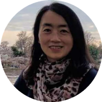 Headshot of Yan Wang, MD PhD, wearing glasses and a light top, looking at the camera with a soft, horizontal blinds background.