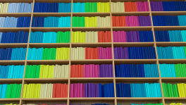 A wall of books arranged by color to create a rainbow stripe pattern on the shelves