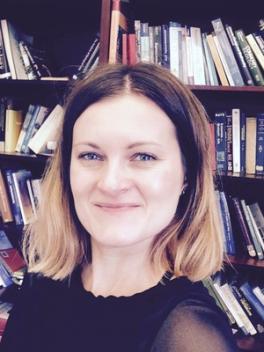 Marta Jarzyna smiling at the camera in front of bookshelves