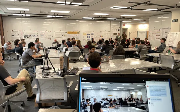 A room full of faculty and students discussing science and research posters hanging on the walls