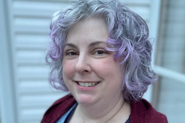 Amy Cogswell, a white woman with silver and violet hair smiles at the camera