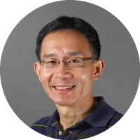 Headshot of Xiaolin Cheng wearing glasses and a collared shirt, smiling against a neutral background.