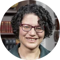 Headshot of Dr. Tanya Berger-Wolf, wearing glasses and a green top, smiling in front of bookshelves.