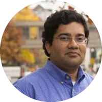 Headshot of Srinivasan Parthasarathy wearing glasses and a blue shirt, photographed outdoors.