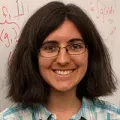 Tamara Broderick smiling at the camera in front of a white board covered with math